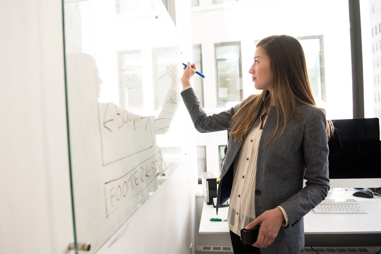 Home Professional woman writing on a whiteboard in an office environment, focusing on ideas.